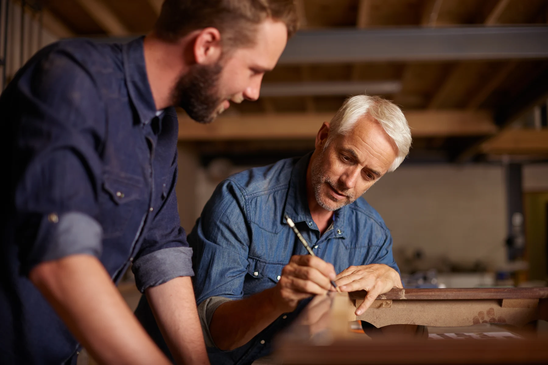 An experienced craftsperson sharing woodworking skills with a colleague